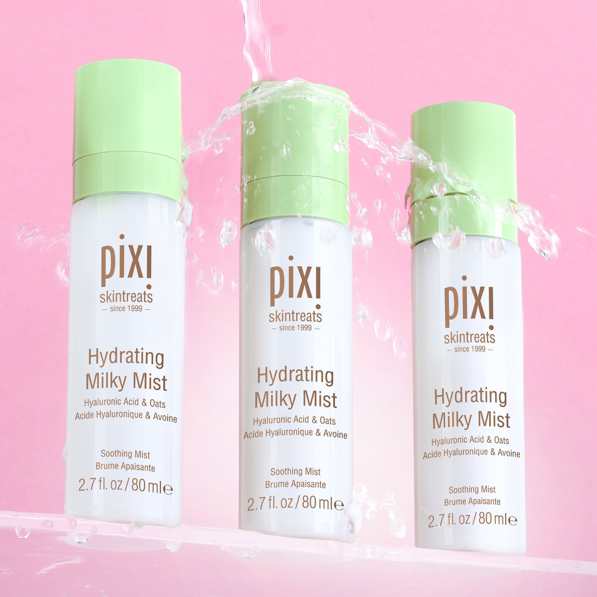 Three bottles of PIXI Hydrating Milky Mist on a pink background