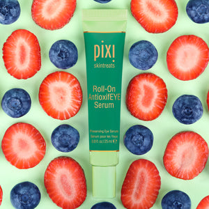  PIXI Roll-On AntioxidEYE Serum surrounded by sliced strawberries and blueberries on a green background